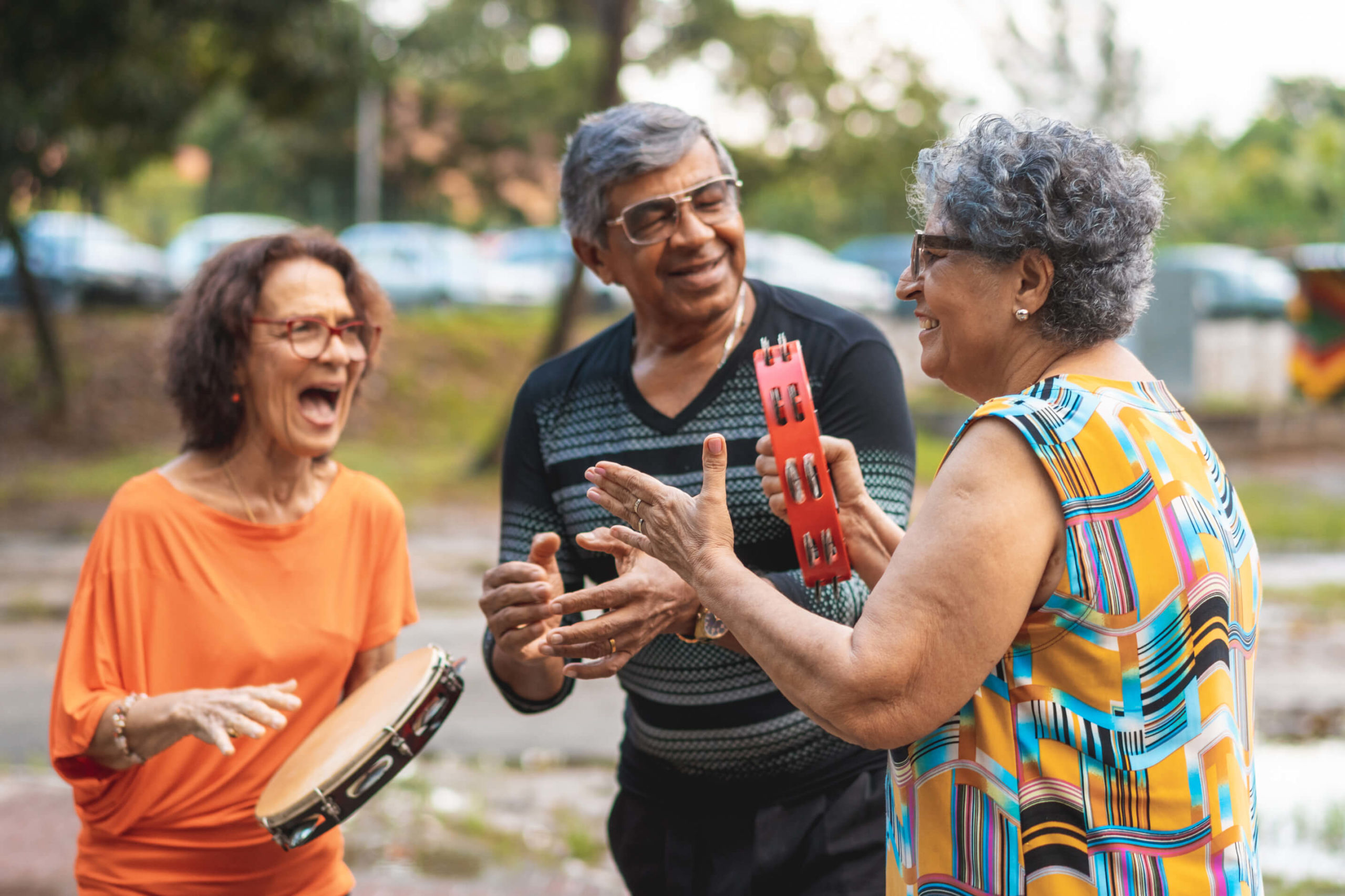 Group of residents playing music together outside using tambourines.